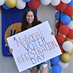 Woman holding sign reading "National Voter Registration Day"